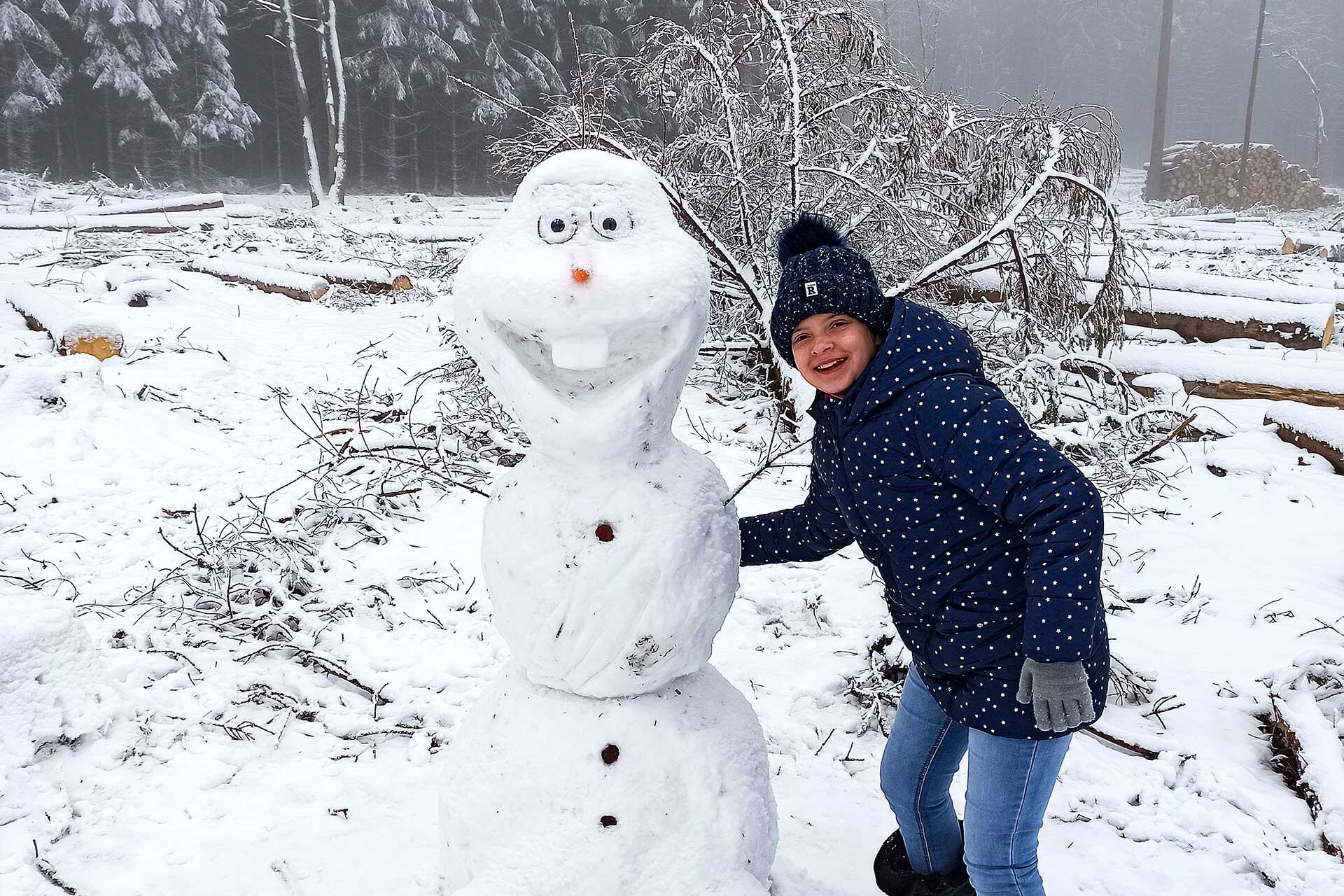 Ein Kind steht neben einem lachenden Schneemann.
