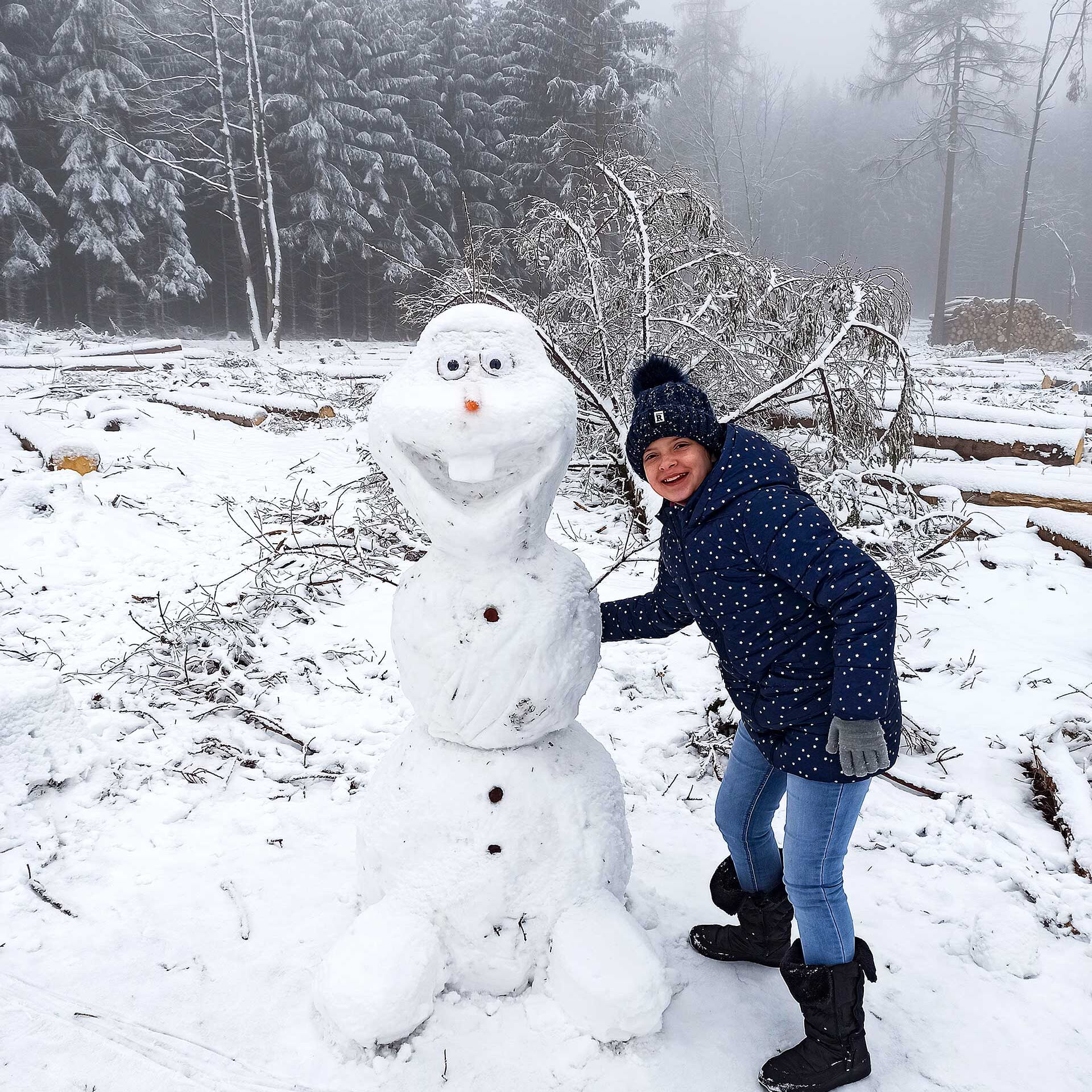Ein Kind steht neben einem lachenden Schneemann.