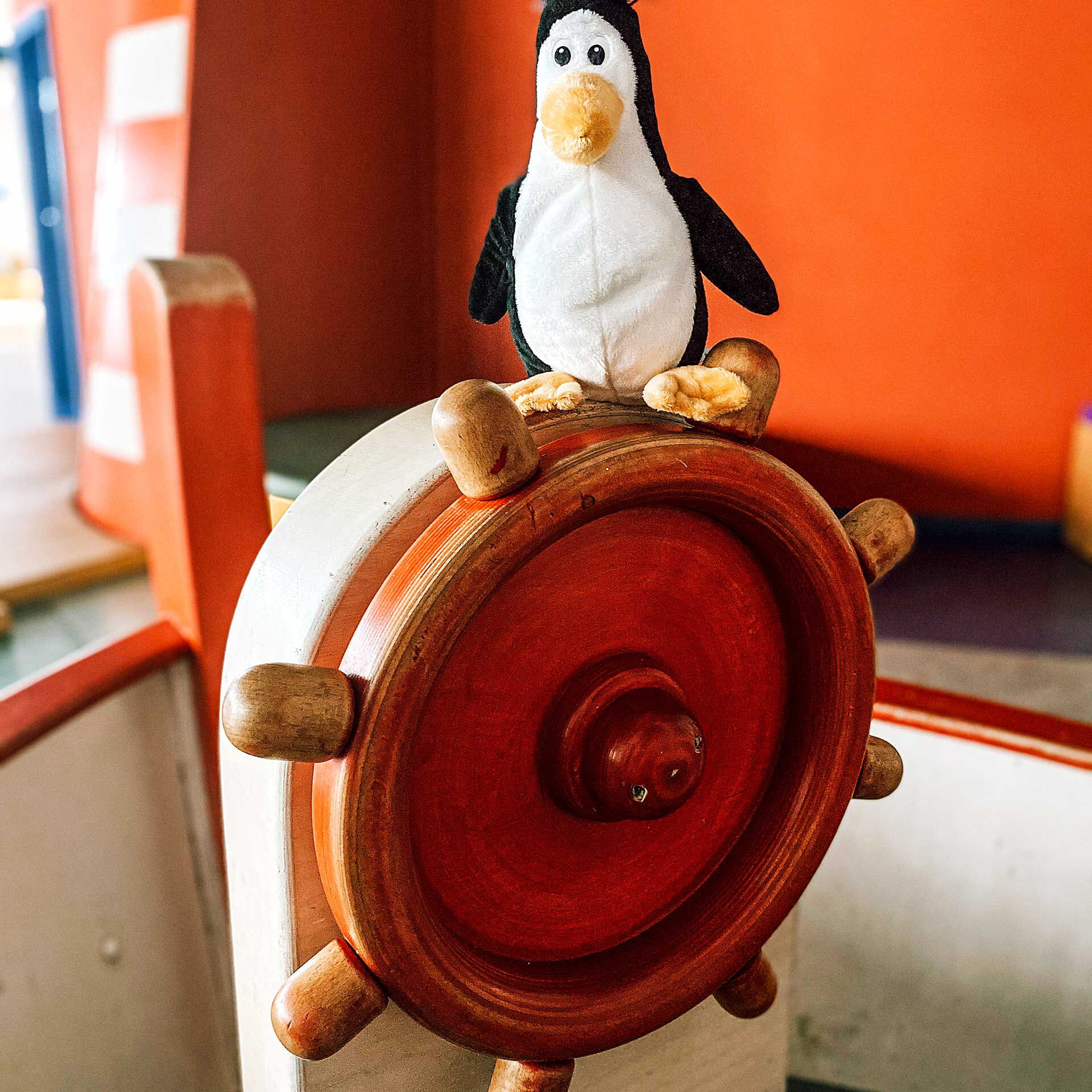Das Steuerrad des Spielzeugschiffs im Pingu Du. Auf dem Steuerrad sitzt der Plüschtier Pinguin.