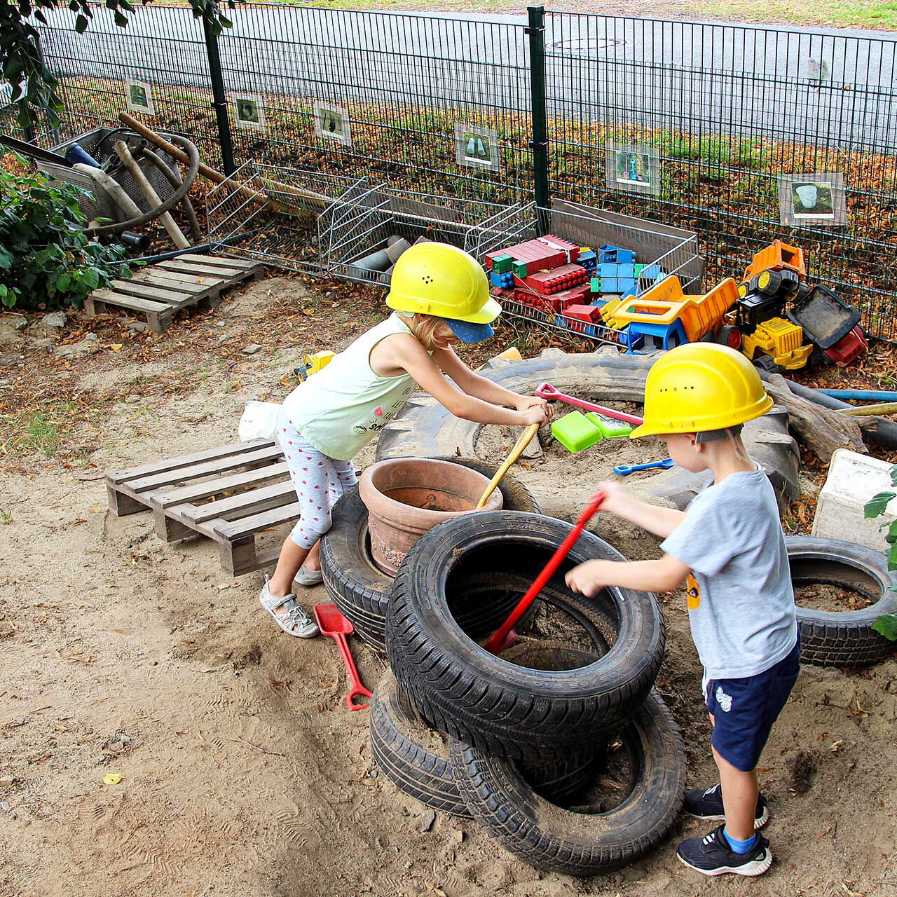 In der Kinderbaustelle spielen zwei Kinder mit alten Reifen, Schaufeln und verschiedensten Baumaterialien.