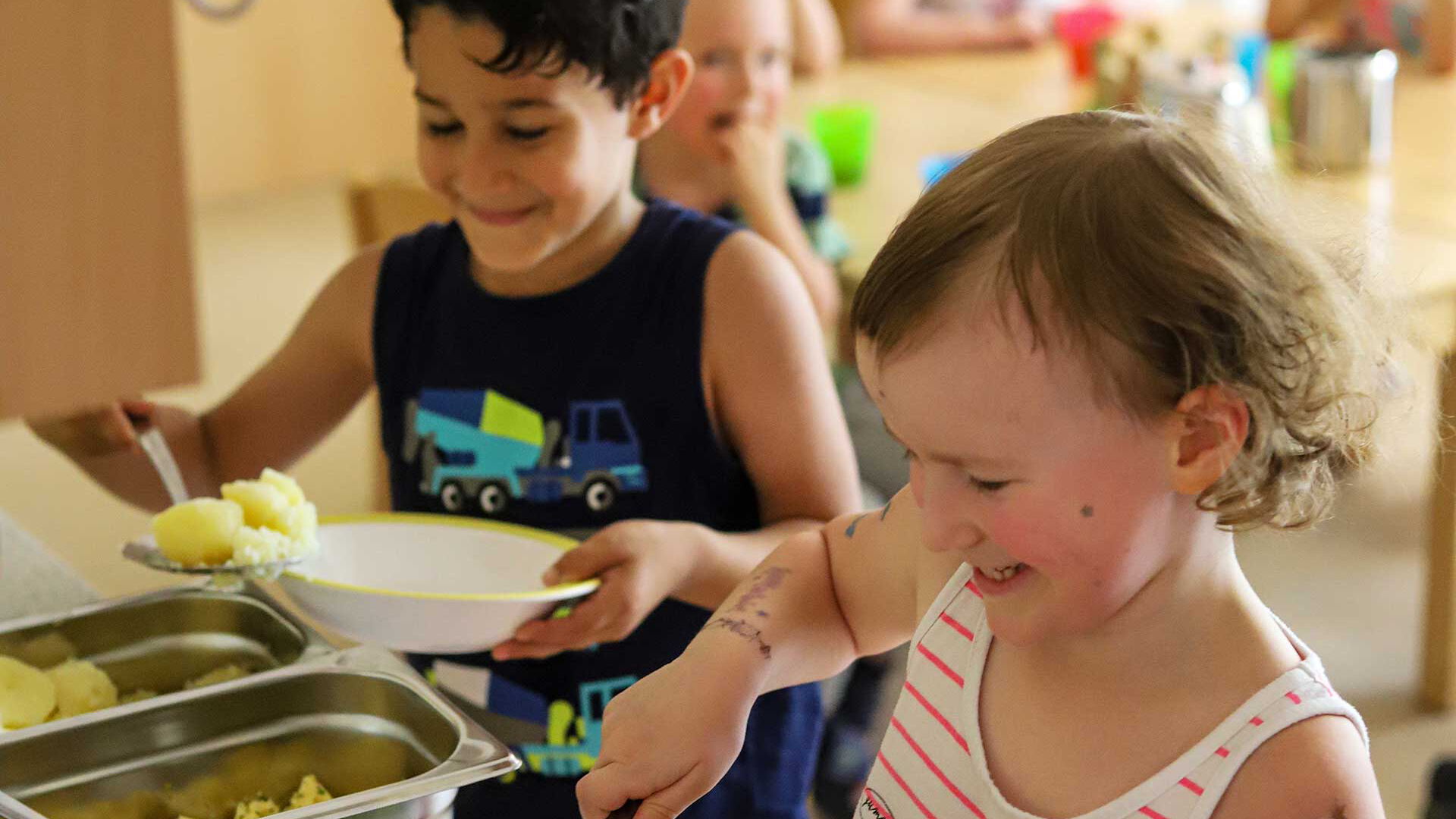 Das Mittagessen wird sich von den Kindern selbst auf den Tellern getan. Es gibt Kartoffeln, Spinat und Ei.