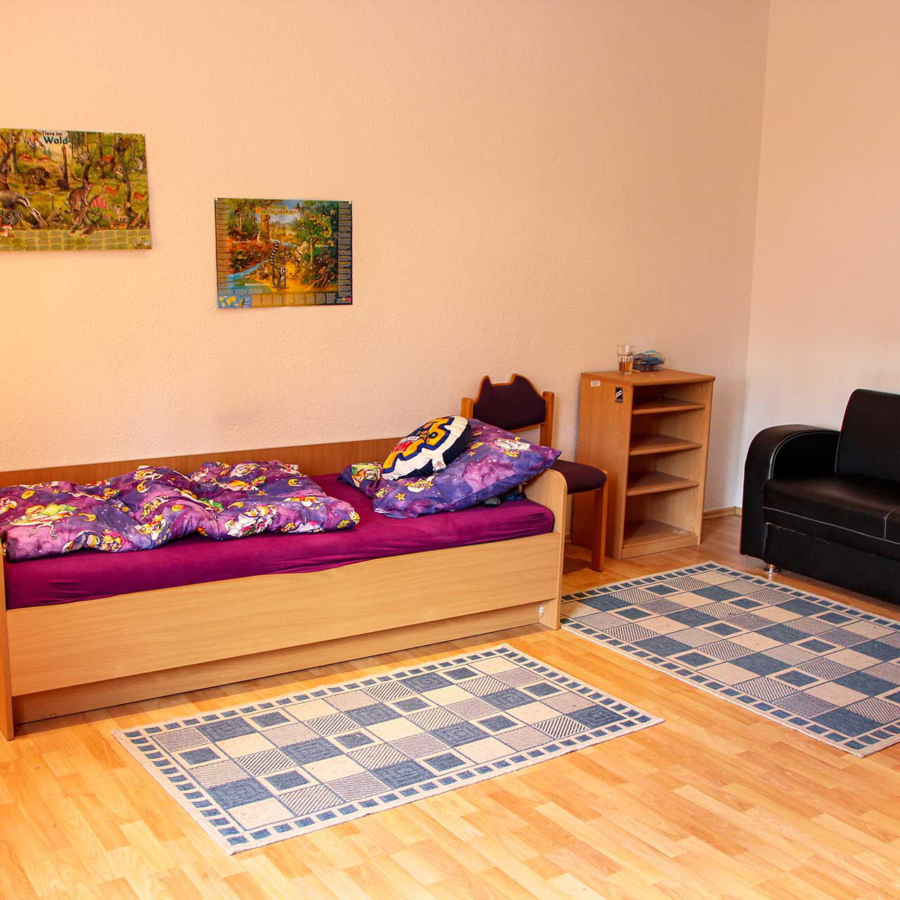 Ein großes Jugendzimmer mit einem Bett und einer Ledercouch.