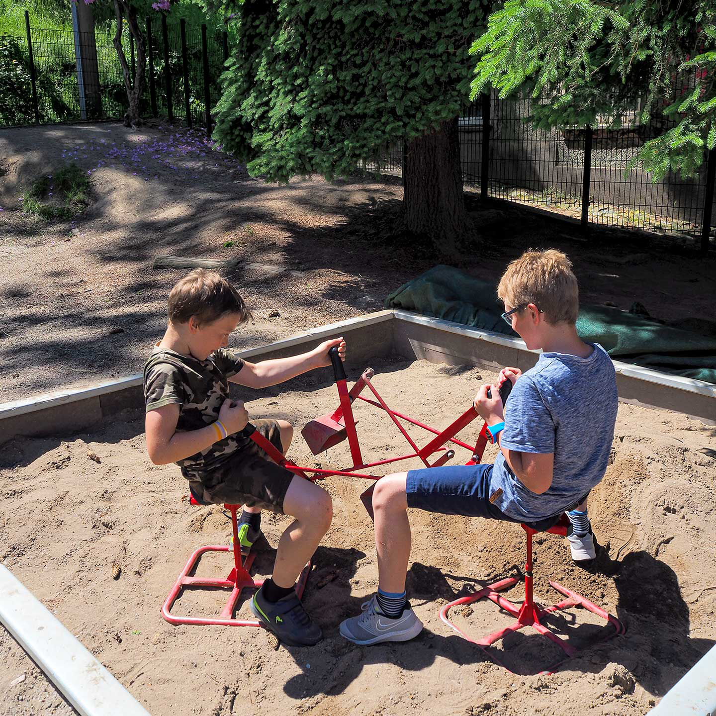 Im Sandkasten spielen zwei Kinder mit den Schaufelbaggern.