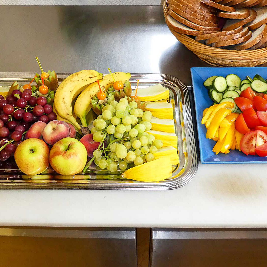 Ein Obst- und Gemüseteller mit einem Brotkorb auf einem Tisch.