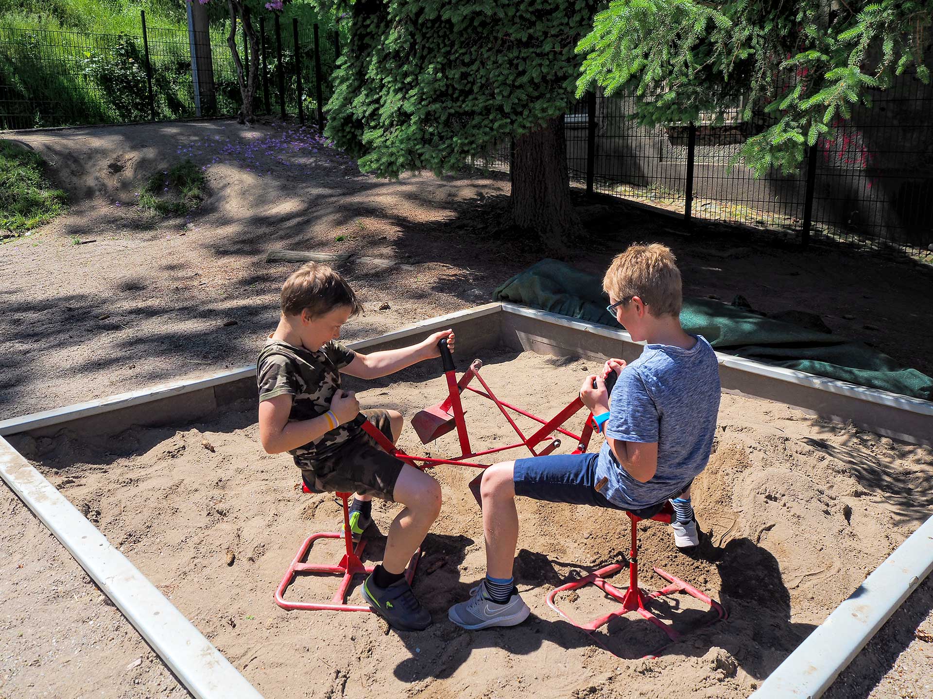 Im Sandkasten spielen zwei Kinder mit den Schaufelbaggern.